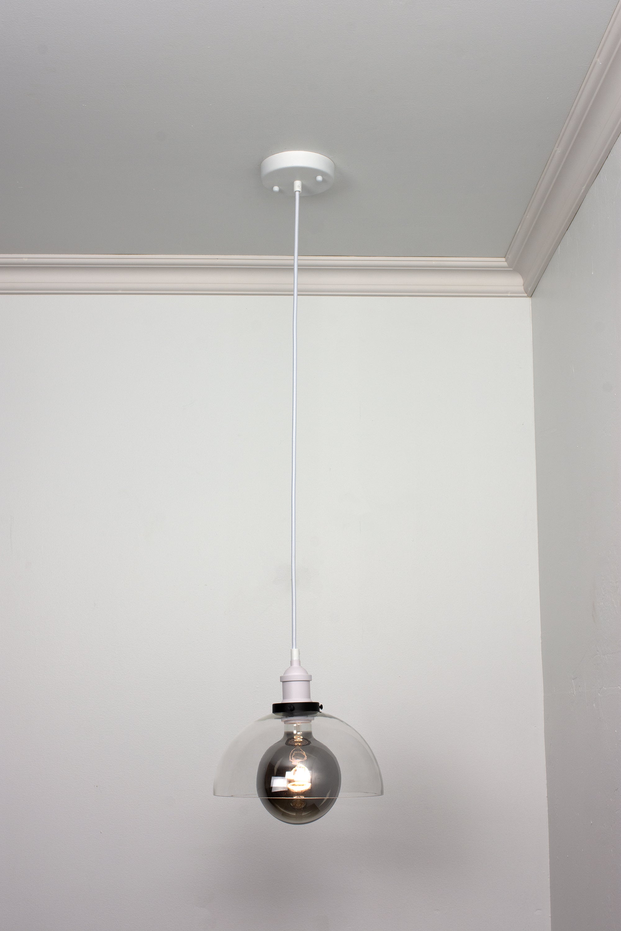 White pendant light with glass dome shade and smoke light bulb