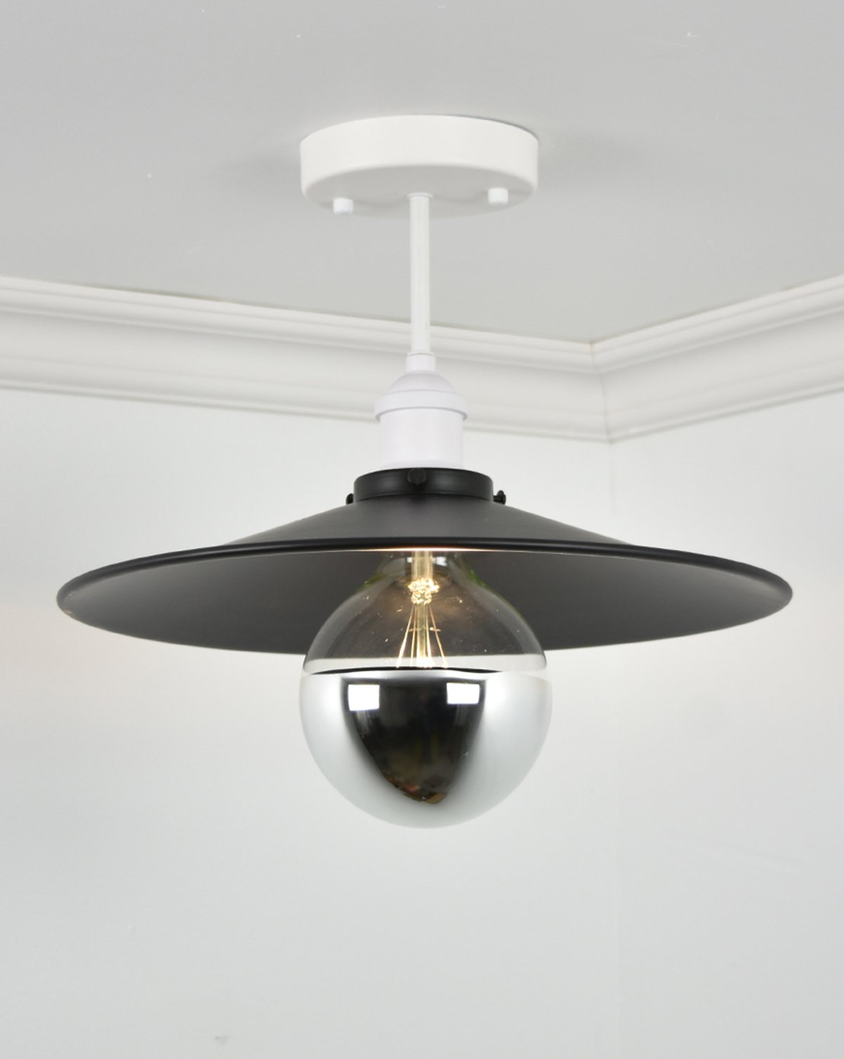 Semi-flush mount light fixture with a white base, wide black shade, and an chrome dipped bulb.