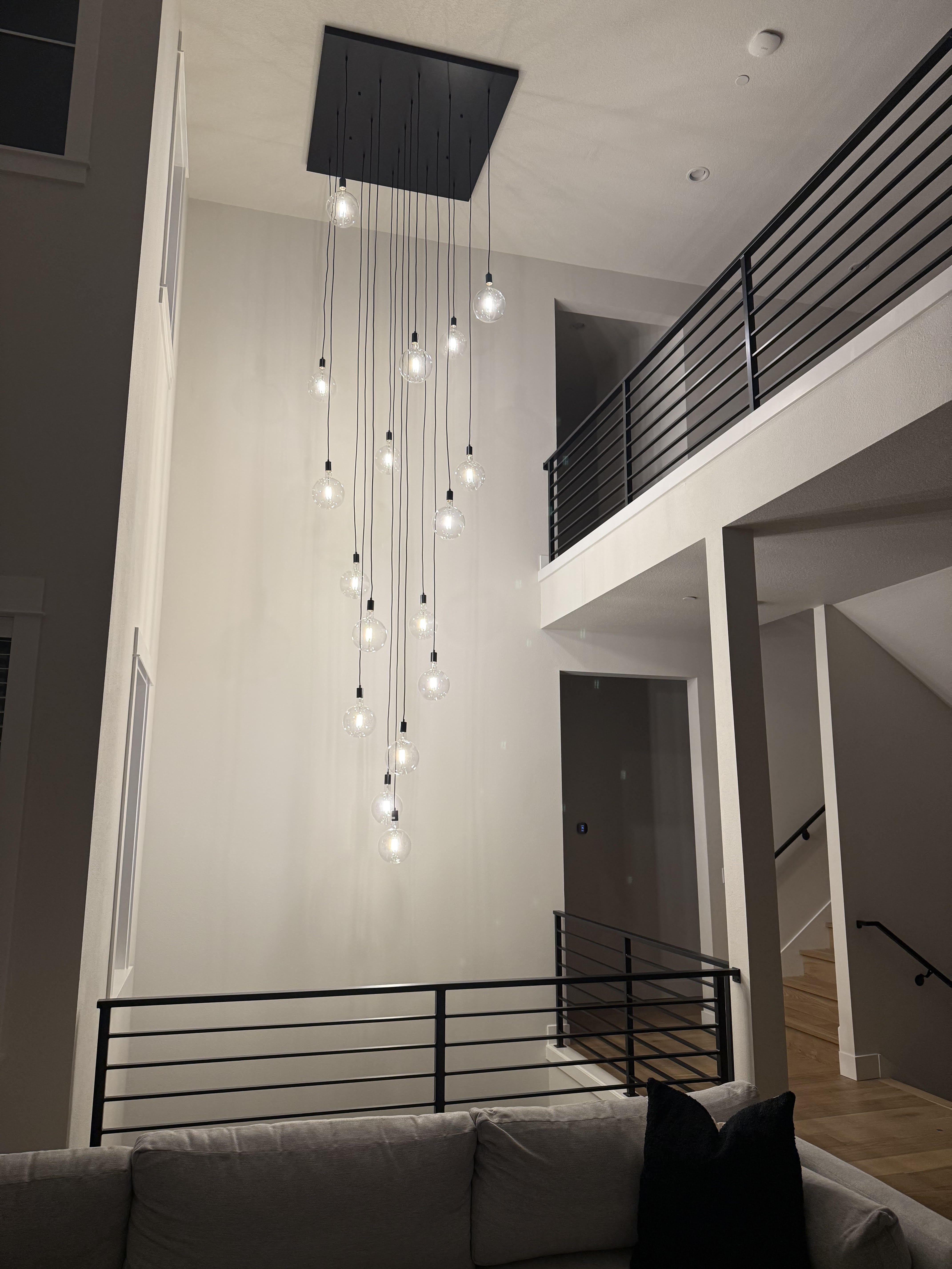 Modern interior with a square base chandelier hanging from the ceiling and 17 globe pendants
