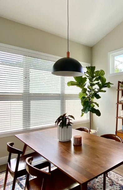 Modern dining room with wooden table, chairs, and a bookshelf. Black dome pendant light