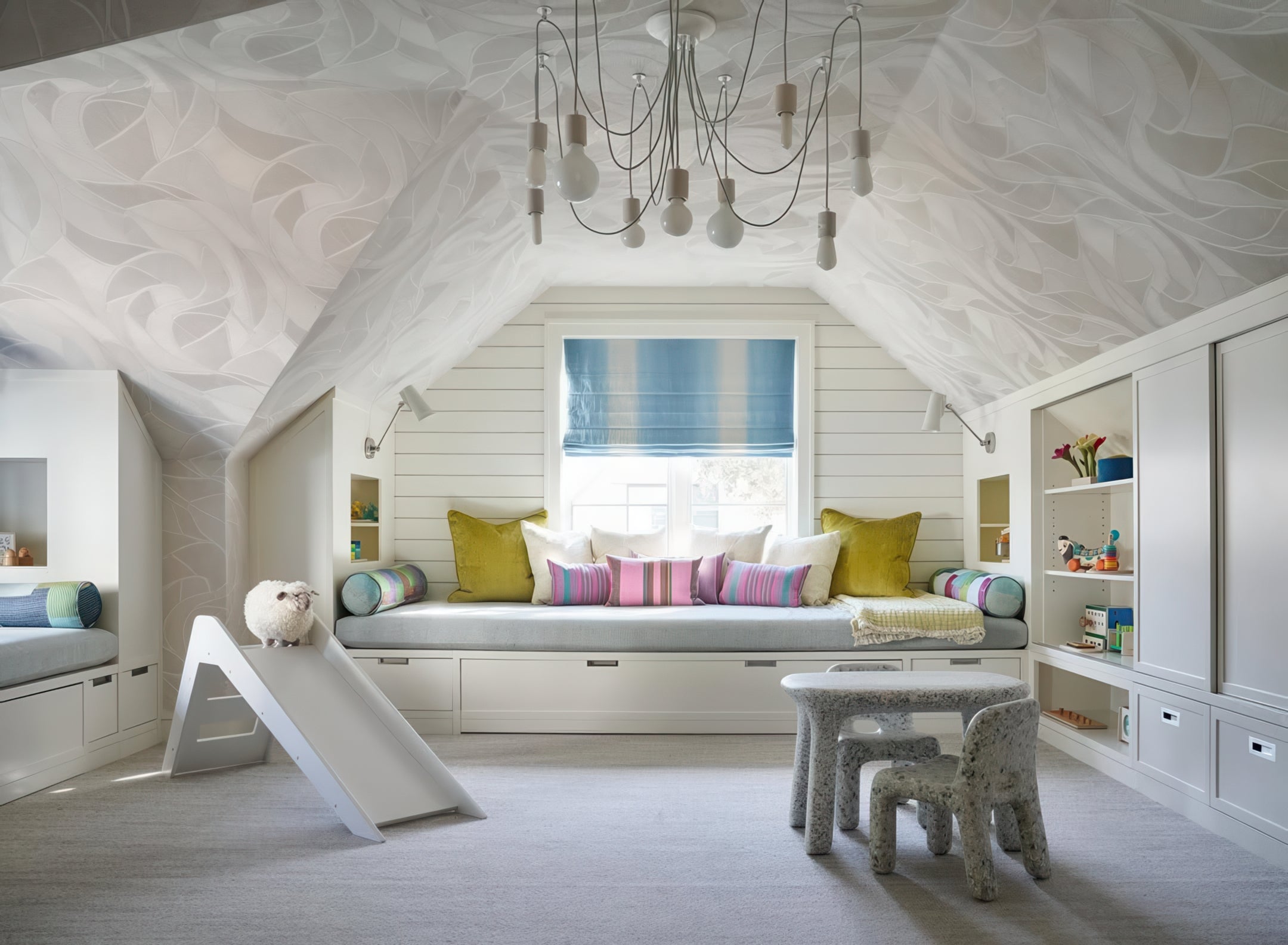 Children's room with slide, bed, and shelves in a attic space. White lighting chandlier