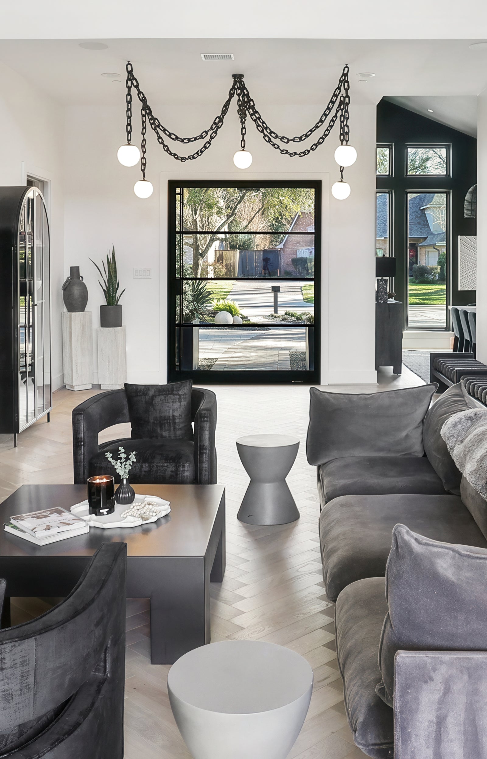 Modern living room with gray sofa, black armchair, and decorative elements. large chandelier