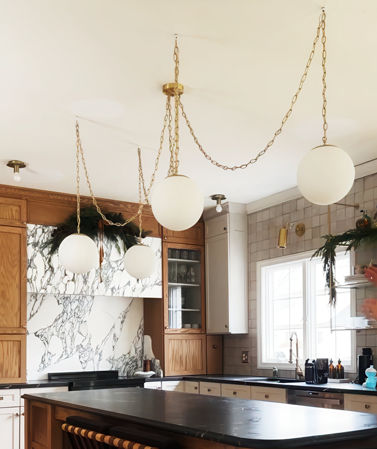 Brass chain swag chandelier with 10" white globe bulbs over a modern kitchen island. Unique lighting upgrade. 