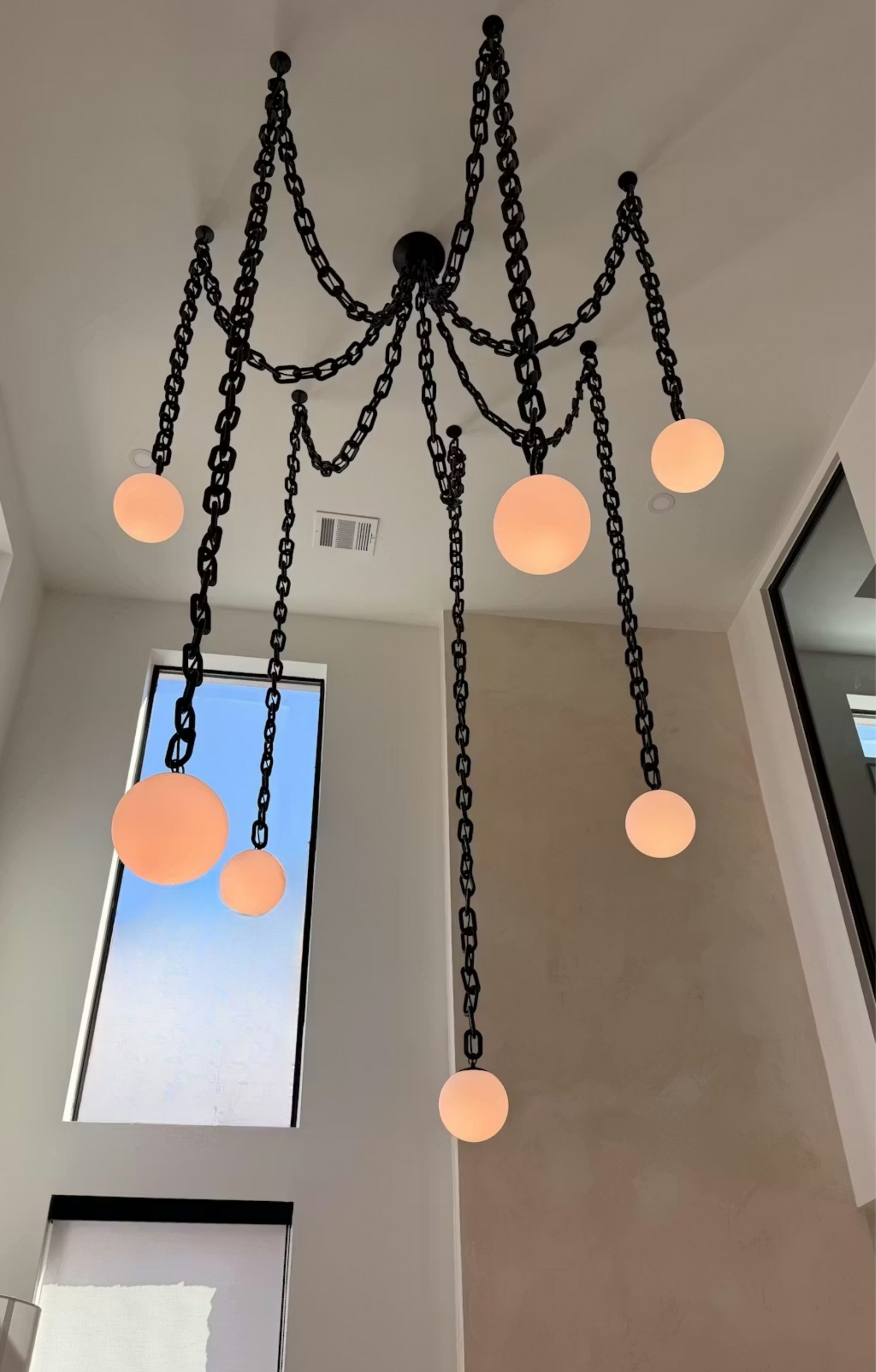 2 story living room with large modern black chain and white globe chandelier with 7 pendants