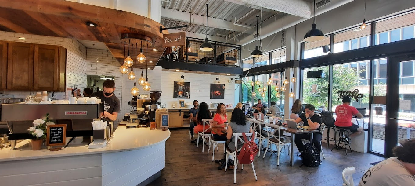 Modern coffee shop interior with customers and staff at tables and counter and pendant lighting
