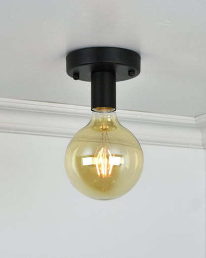 Flush mount light fixture with a black base and a large, round exposed bulb installed on a ceiling.