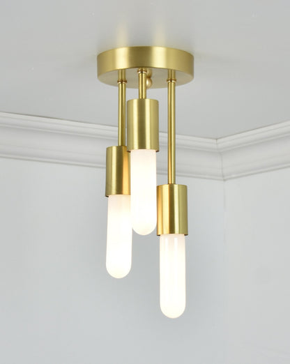 Semi-flush mount light fixture with a brushed brass base and three hanging bulbs with matching brass cylindrical housings.